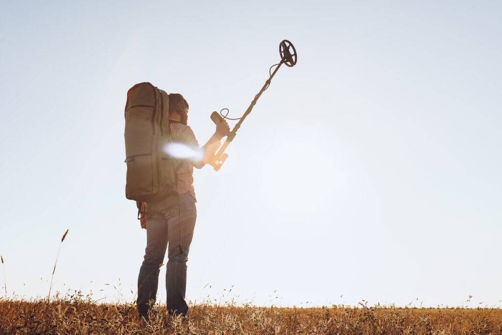 Man with metal detector equipment searching for metal goods in the field